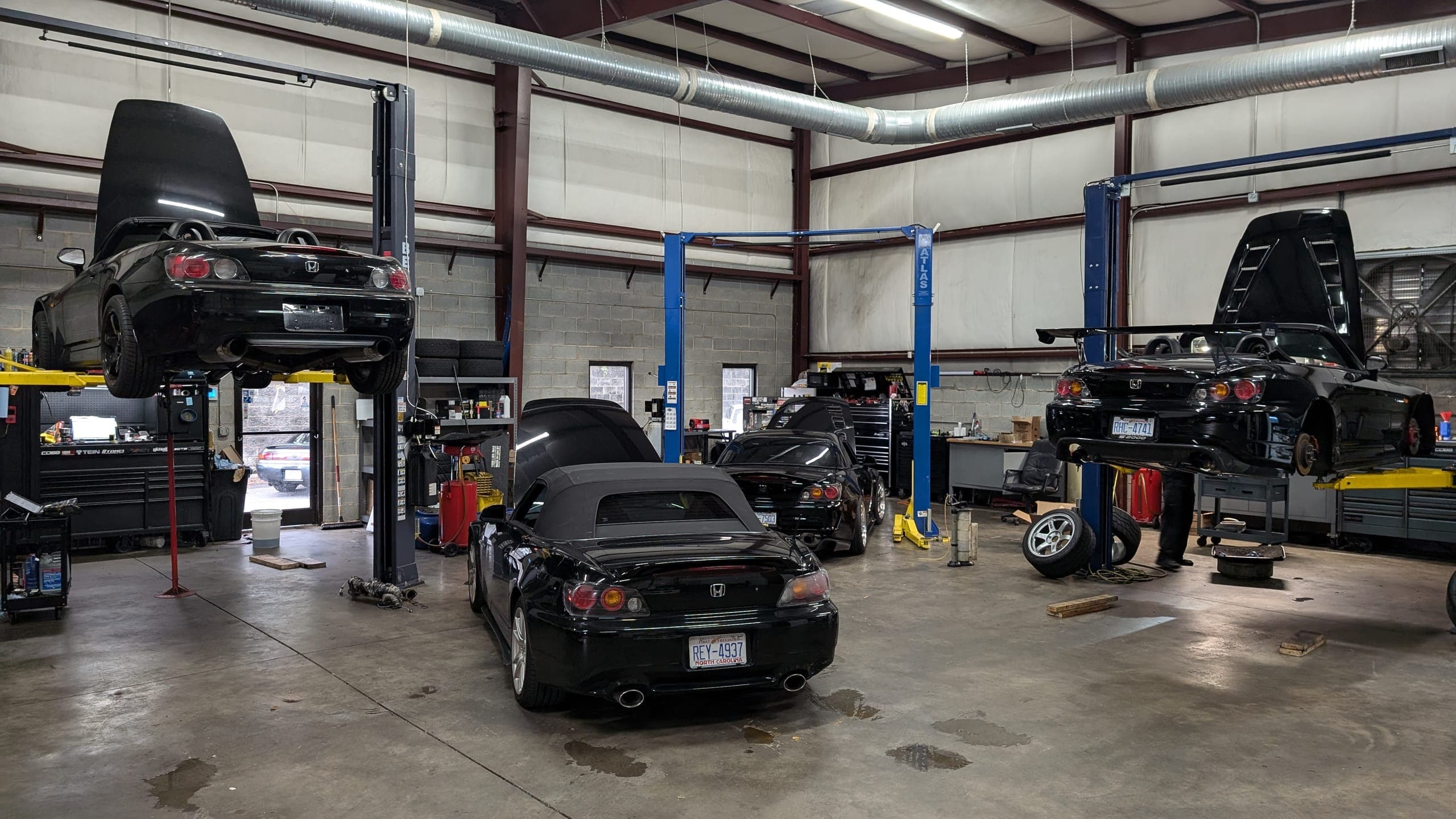 Three black Honda S2000s in the Streamline Performance Garage service bays in Concord, NC, two of them raised on lifts